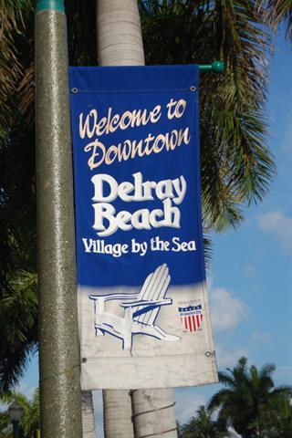 A blue and white sign that says welcome to downtown debray beach village by the sea