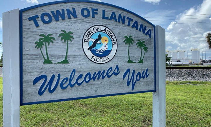 A welcome sign for the town of lantana is sitting in the grass.