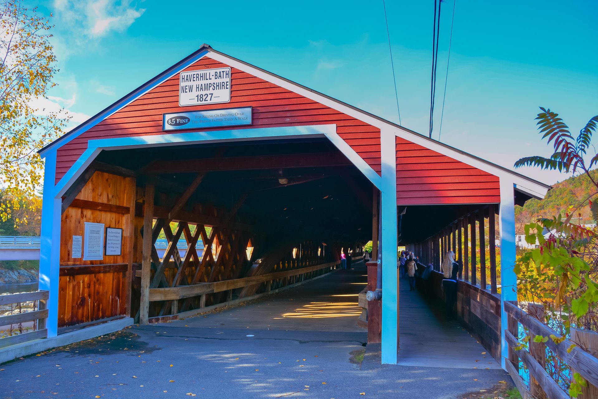 A red and blue covered bridge with a sign on it